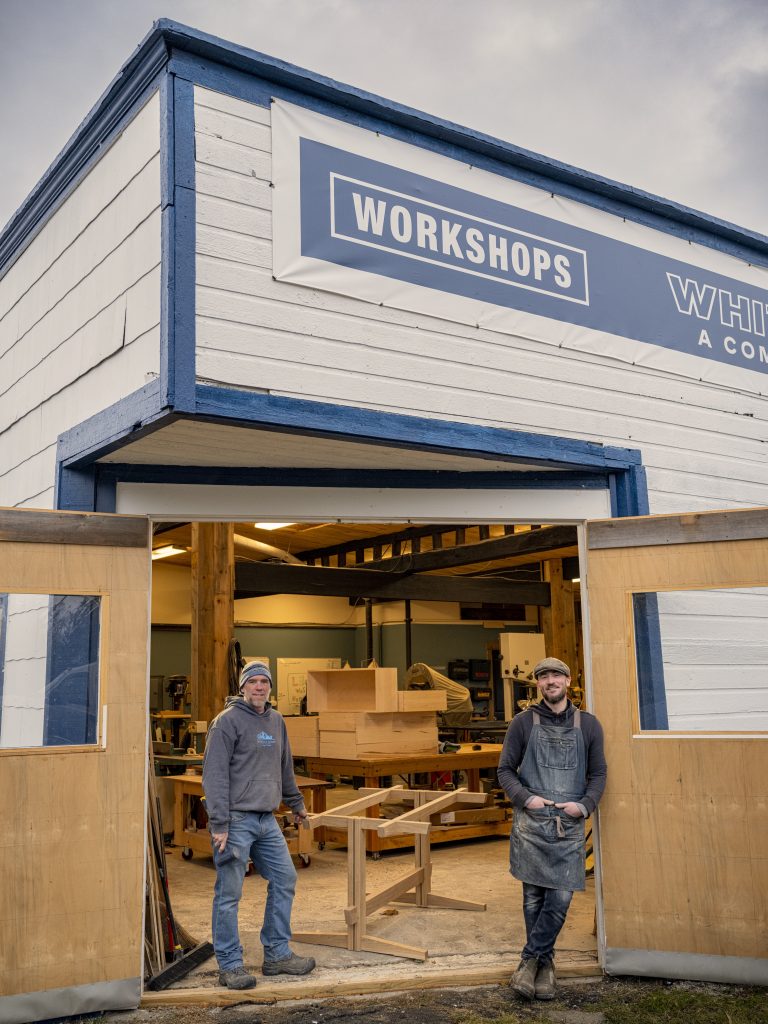 Two men stand at doorway to woodshop in renovated garage