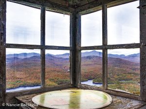view of mountains, lake and fall foliage seen through windows of a fire tower