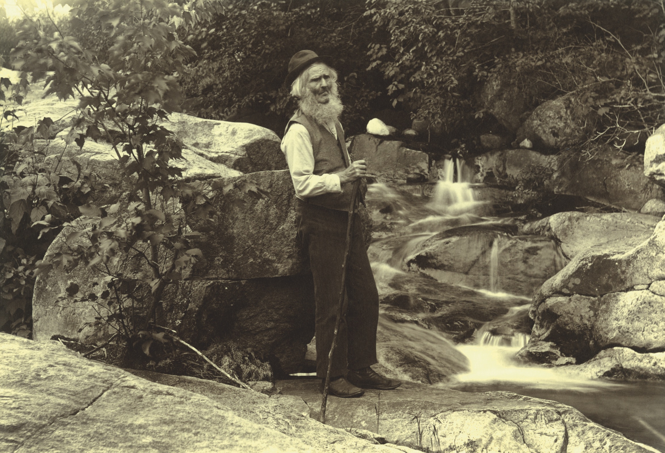a man with a long white beard stands by a stream