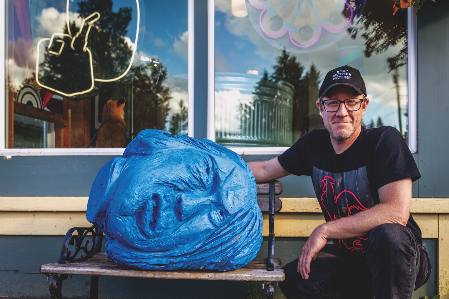 Artist Daniel A. Bruce outside his gallery with a blue head sculpture